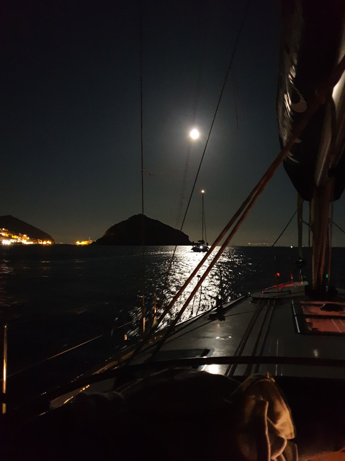 Barca a vela in rada di notte con la luna piena