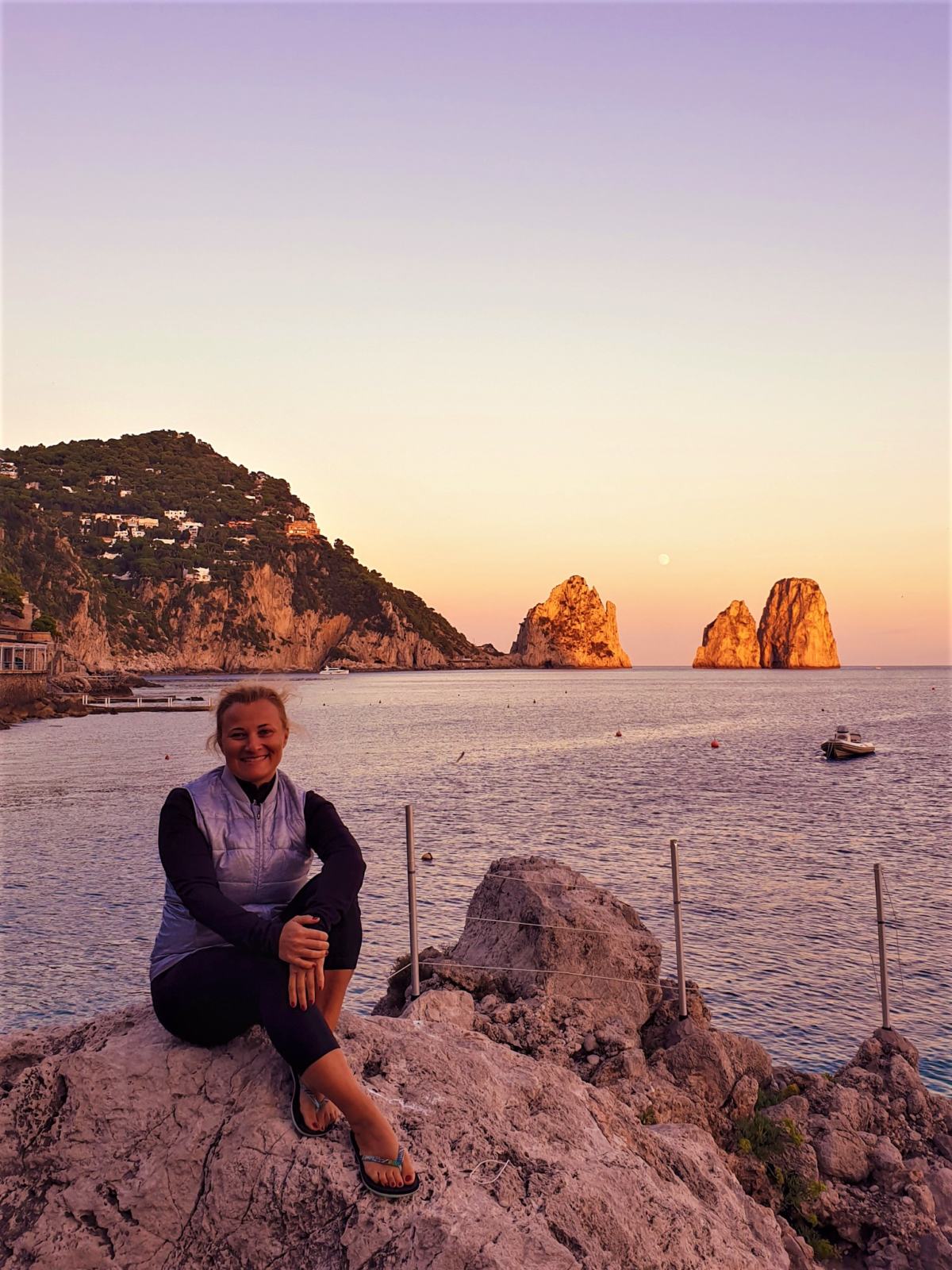 Io seduta in spiaggia e alle mie spalle i Faraglioni di Capri all'ora del tramonto